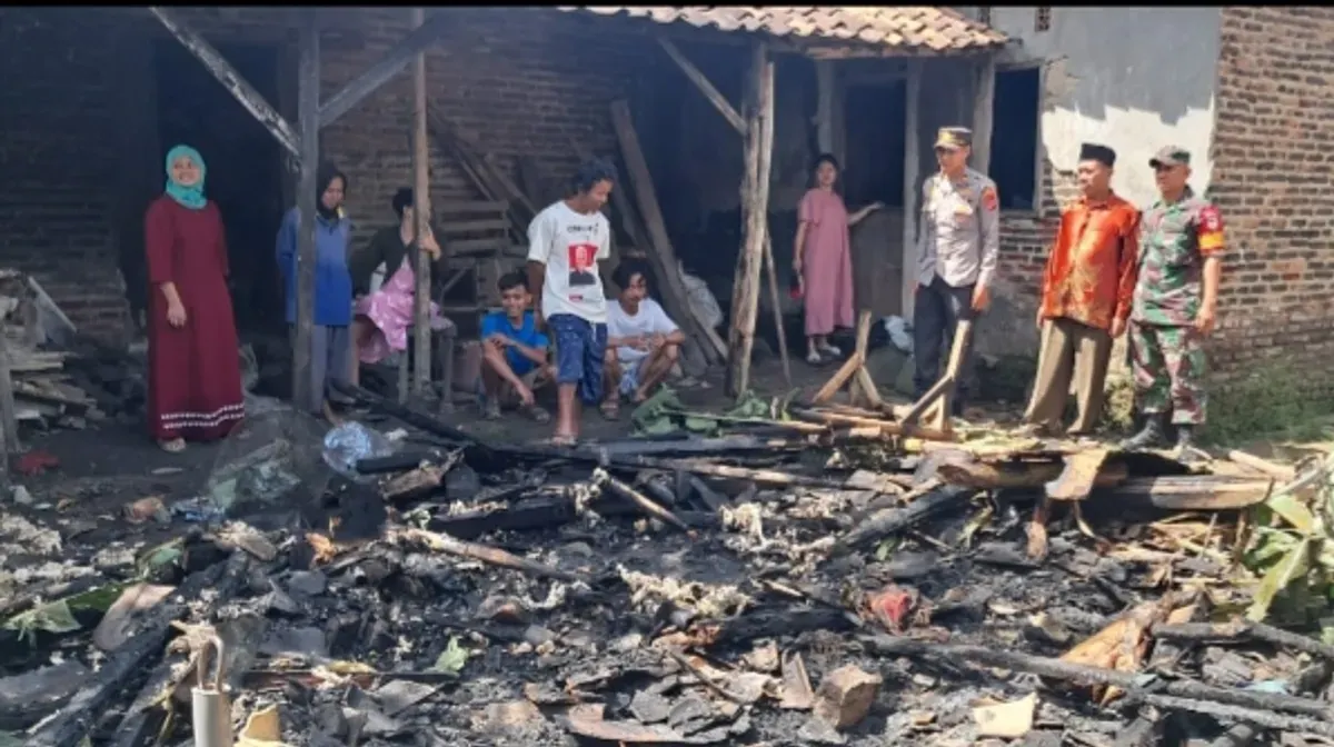 Kapolsek Cikeusal Iptu Hairus Saleh saat melihat kondisi rumah Arkiman yang rata dengan tanah setelah dilalap si jago merah. (Sumber: Polsek Cikeusal)