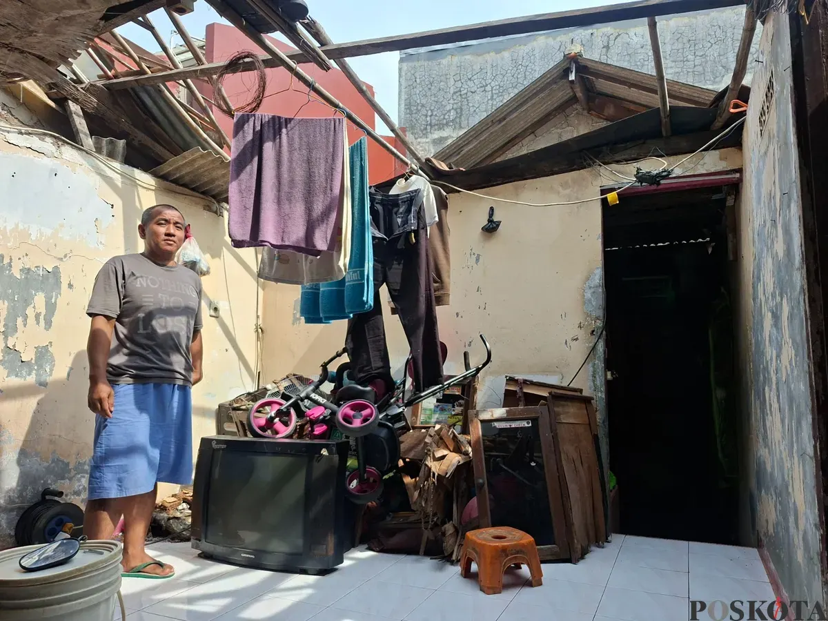 Dodi, 40 tahun, berdiri di area rumahnya yang mengalami kerusakan parah pada bagian atap di Depok. Kondisi rumah tanpa atap membuat para penghuninya terpaksa mengungsi saat turun hujan. (Sumber: Poskota/Angga Pahlevi)