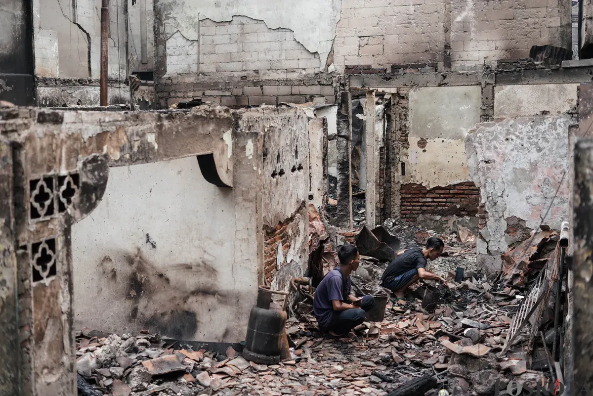 Warga berjalan di antara puing-puing sisa kebakaran rumah di pemukiman padat penduduk Taman Sari, Jakarta Barat, Senin, 29 September 2025. (Sumber: Poskota/Bilal Nugraha Ginanjar)