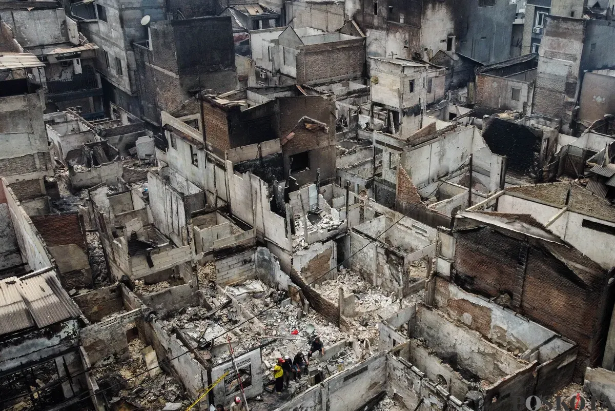 Warga berjalan di antara puing-puing sisa kebakaran rumah di pemukiman padat penduduk Taman Sari, Jakarta Barat, Senin, 29 September 2025. (Sumber: Poskota/Bilal Nugraha Ginanjar)