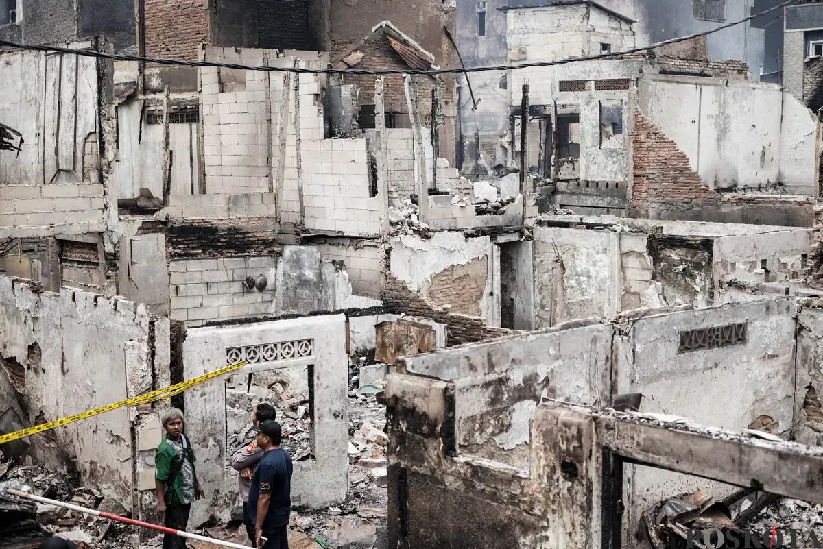 Warga berjalan di antara puing-puing sisa kebakaran rumah di pemukiman padat penduduk Taman Sari, Jakarta Barat, Senin, 29 September 2025. (Sumber: Poskota/Bilal Nugraha Ginanjar)