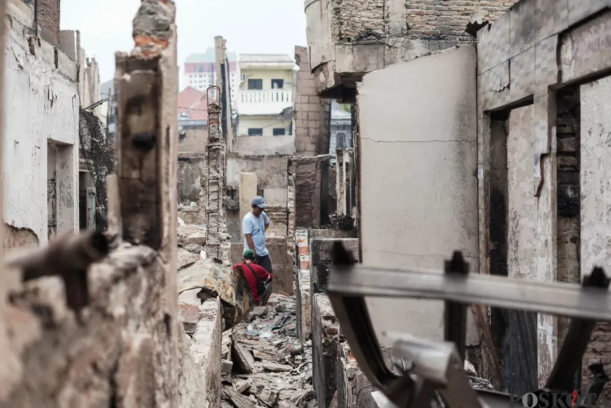 Warga berjalan di antara puing-puing sisa kebakaran rumah di pemukiman padat penduduk Taman Sari, Jakarta Barat, Senin, 29 September 2025. (Sumber: Poskota/Bilal Nugraha Ginanjar)