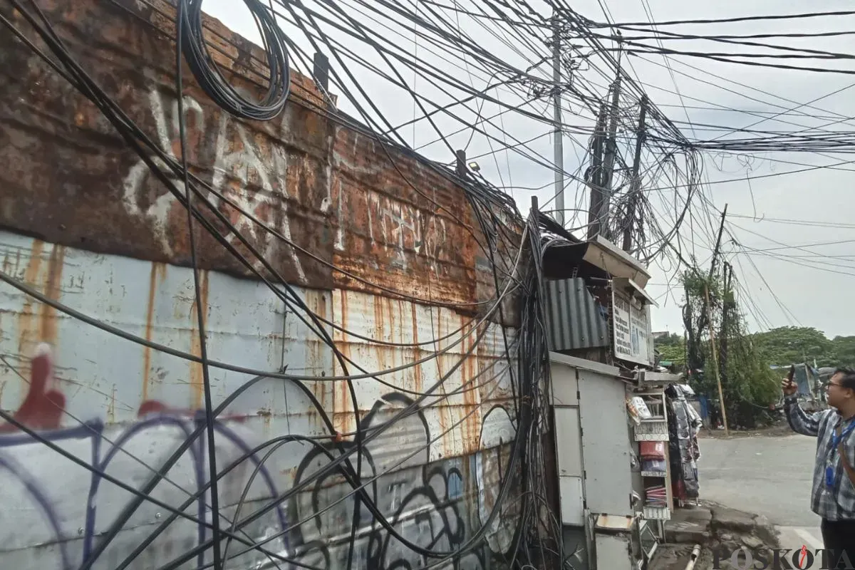 Penampakan kabel semeratut bahkan menjuntai ke bawah di Jalan Raya Kapuk, Penjaringan, Jakarta Utara, Jumat, 3 Oktober 2025. (Sumber: Poskota/Pandi Ramedhan)