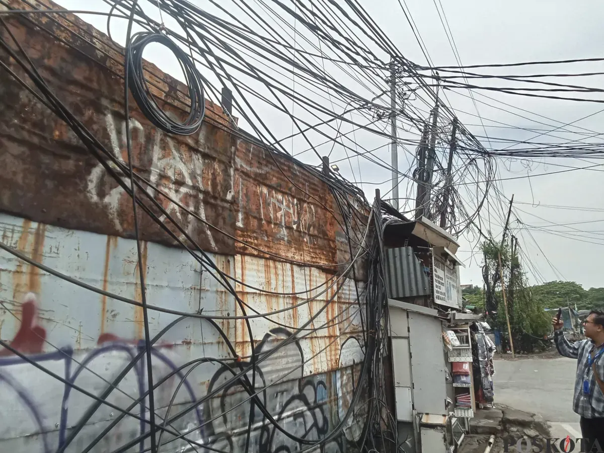 Penampakan kabel semeratut bahkan menjuntai ke bawah di Jalan Raya Kapuk, Penjaringan, Jakarta Utara, Jumat, 3 Oktober 2025. (Sumber: Poskota/Pandi Ramedhan)