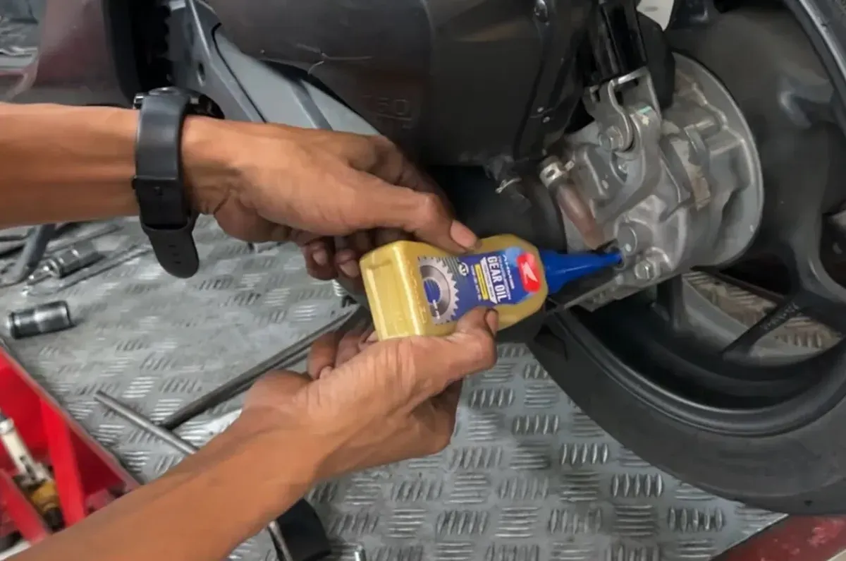 Mekanik sedang memeriksa dan mengganti oli gardan pada motor matik untuk menjaga performa dan keawetan komponen transmisi akhir. (Sumber: Istimewa)