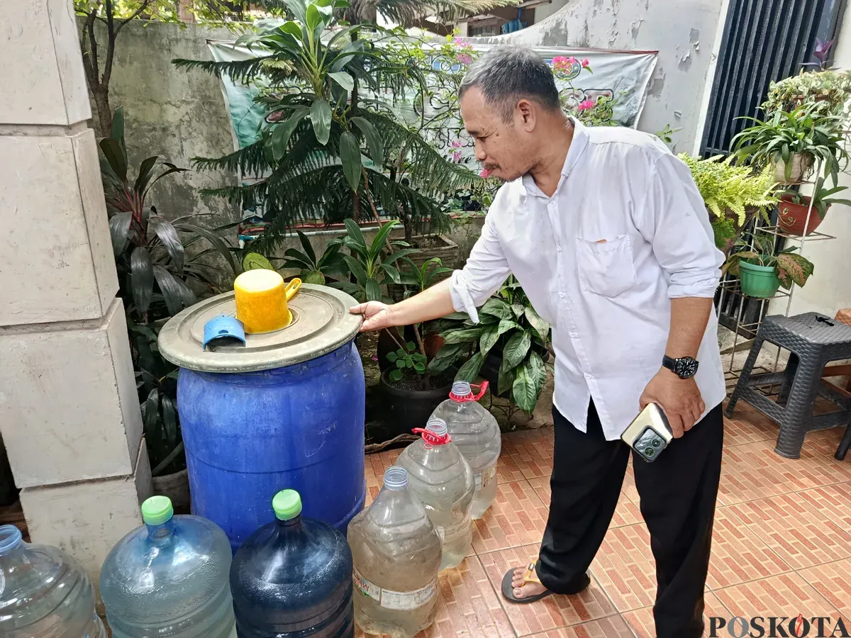 Joko, Ketua RT 08/RW 018, menunjukkan air bantuan dari distribusi PDAM Tirta Patriot yang ia tampung di galon hingga gentong di halaman rumahnya. (Sumber: POSKOTA | Foto: Nurpini Aulia Rapika)