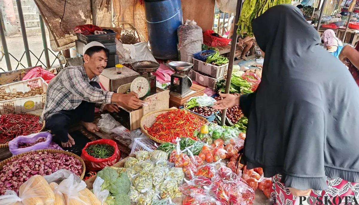 Hasanudin, pedagang sayur di Pasar Baru Bekasi Timur sedang melayani pembeli di lapaknya, Selasa, 7 Oktober 2025. (Sumber: POSKOTA | Foto: Nurpini Aulia Rapika)