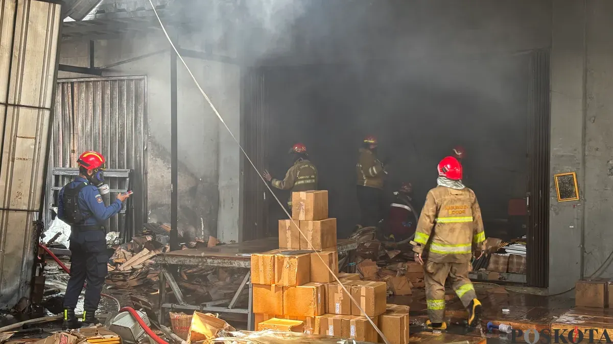 Petugas pemadam melakukan pendinginan di pabrik bingkai yang terbakar pada Selasa pagi 7 Oktober 2025, di Jalan Cikaret, Cibinong, Kabupaten Bogor. (Sumber: Poskota/M. Tegar Jihad)