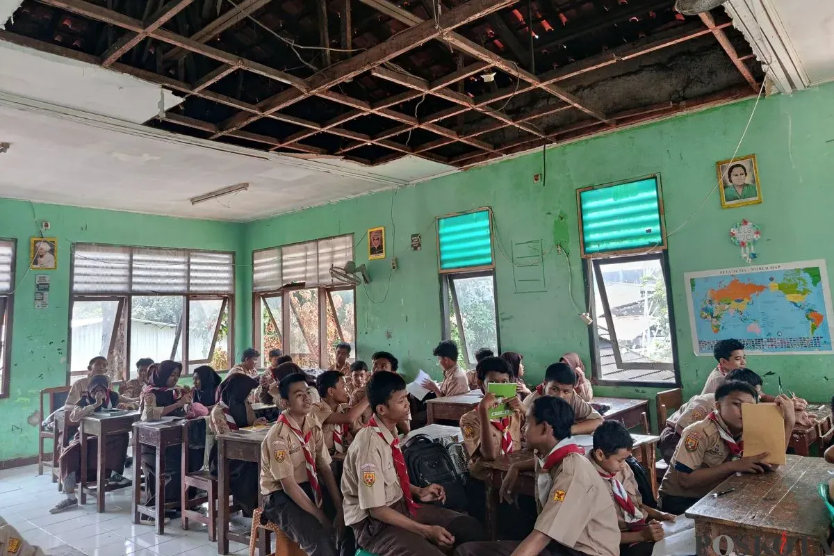 Suasana sejumlah siswa USB SMPN 62 Kota Bekasi mengikuti kegiatan belajar mengajar di ruang kelas dengan atap nyaris roboh, Rabu, 8 Oktober 2025. (Sumber: Poskota/Nurpini Aulia Rapika)