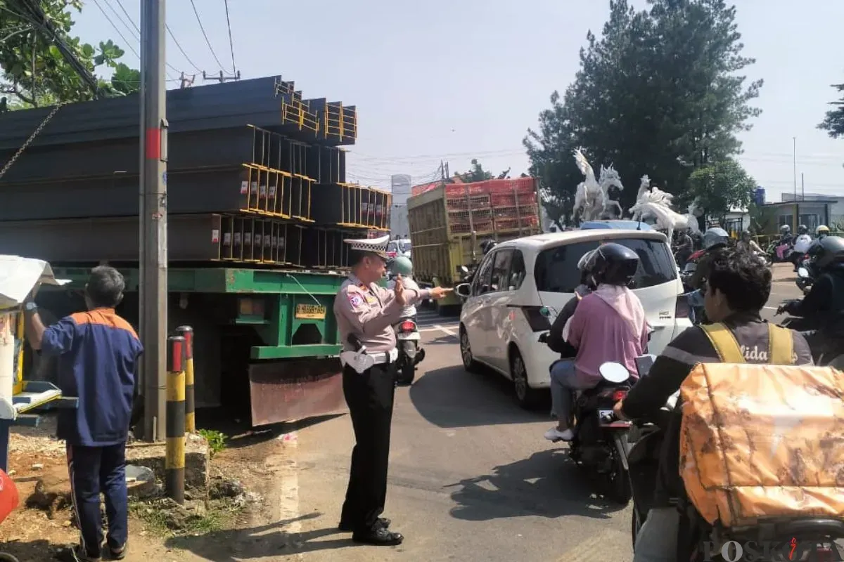 Kanit Lantas Polsek Bojongsari, Iptu Suwardi mengatur lalu lintas di lokasi truk besi anjlok di Jalan Raya Parung-Ciputat, Bojongsari, Kota Depok, Jumat, 10 Oktober 2025. (Sumber: Poskota/Angga Pahlevi)