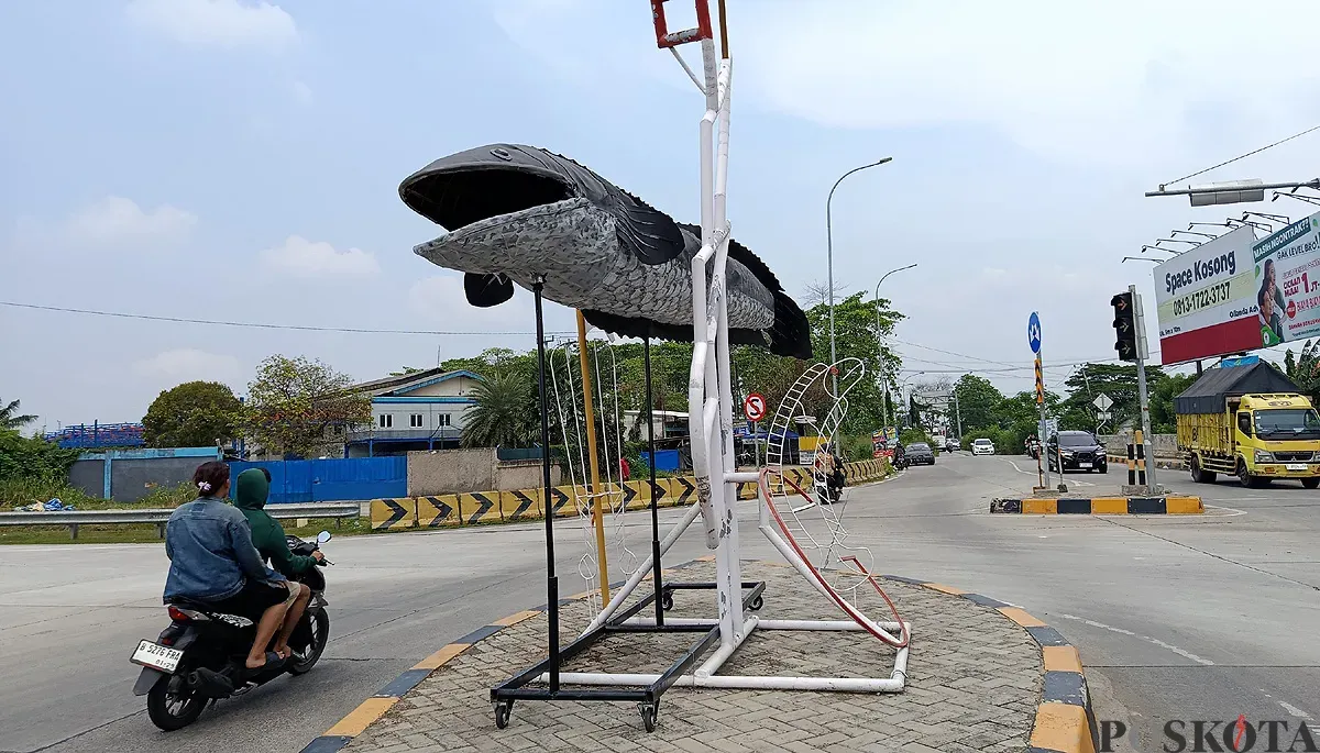 Penampakan patung ikan gabus yang berdiri di depan exit Tol Gabus, Desa Srijaya, Kecamatan Tambun Utara, Kabupaten Bekasi. (Sumber: POSKOTA | Foto: Nurpini Aulia Rapika)