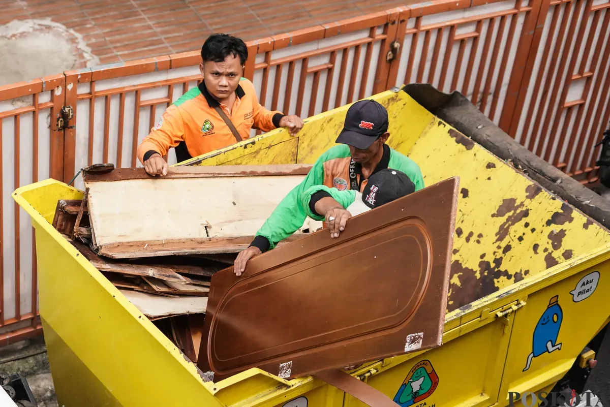 Petugas Dinas Lingkungan Hidup Kota Jakarta Timur mengangkut kayu lemari bekas milik warga menggunakan mobil truk di kawasan Cijantung, Pasar Rebo, Jakarta, Selasa, 21 Oktober 2025. (Sumber: Poskota/Bilal Nugraha Ginanjar)