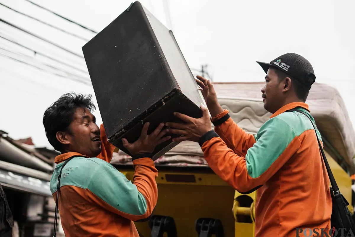 Petugas Dinas Lingkungan Hidup Kota Jakarta Timur mengangkut lemari bekas milik warga menggunakan mobil truk di kawasan Cijantung, Pasar Rebo, Jakarta, Selasa, 21 Oktober 2025. (Sumber: Poskota/Bilal Nugraha Ginanjar)
