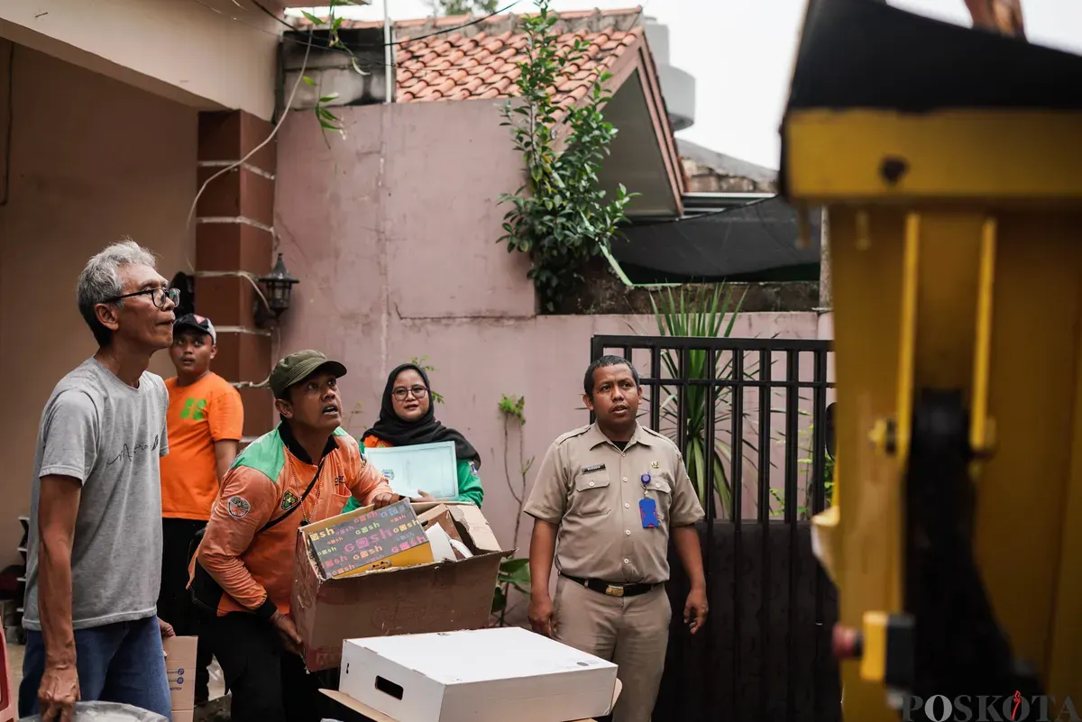 Petugas Dinas Lingkungan Hidup Kota Jakarta Timur mengangkut kayu lemari bekas milik warga menggunakan mobil truk di kawasan Cijantung, Pasar Rebo, Jakarta, Selasa, 21 Oktober 2025. (Sumber: Poskota/Bilal Nugraha Ginanjar)