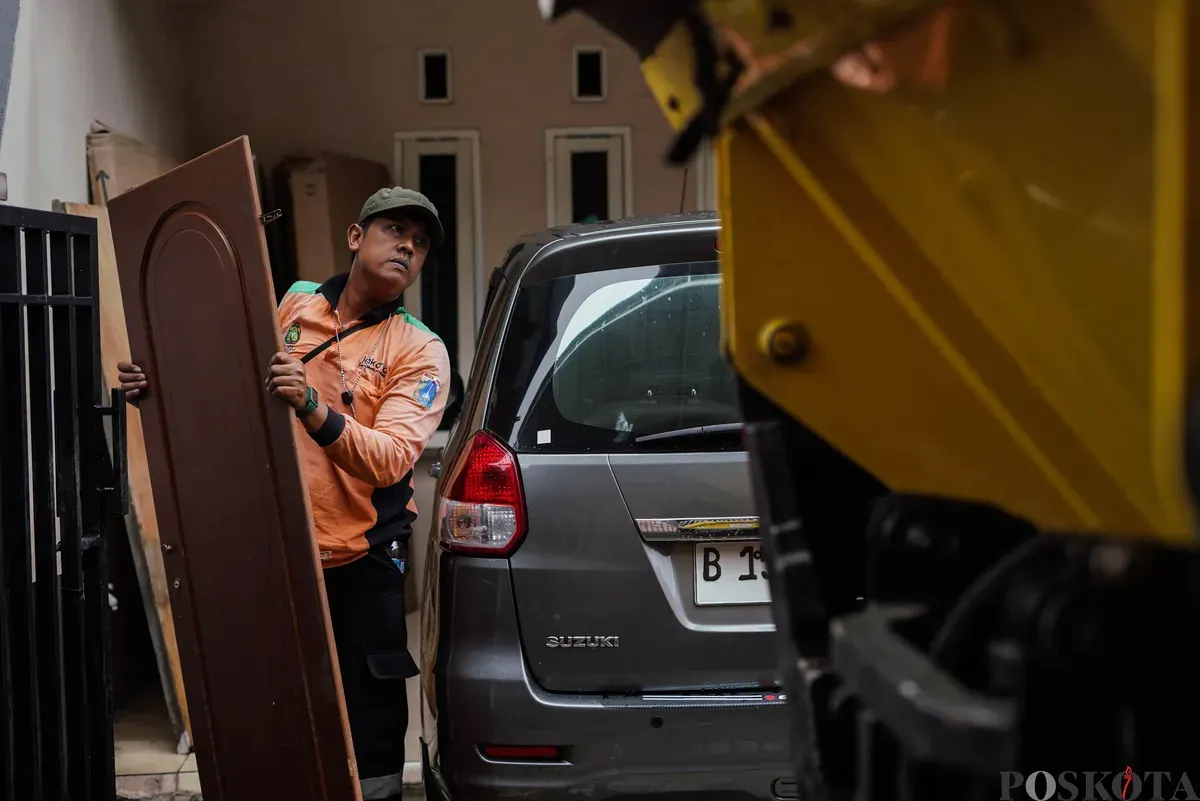 Petugas Dinas Lingkungan Hidup Kota Jakarta Timur mengangkut kayu pintu bekas milik warga menggunakan mobil truk di kawasan Cijantung, Pasar Rebo, Jakarta, Selasa, 21 Oktober 2025. (Sumber: Poskota/Bilal Nugraha Ginanjar)