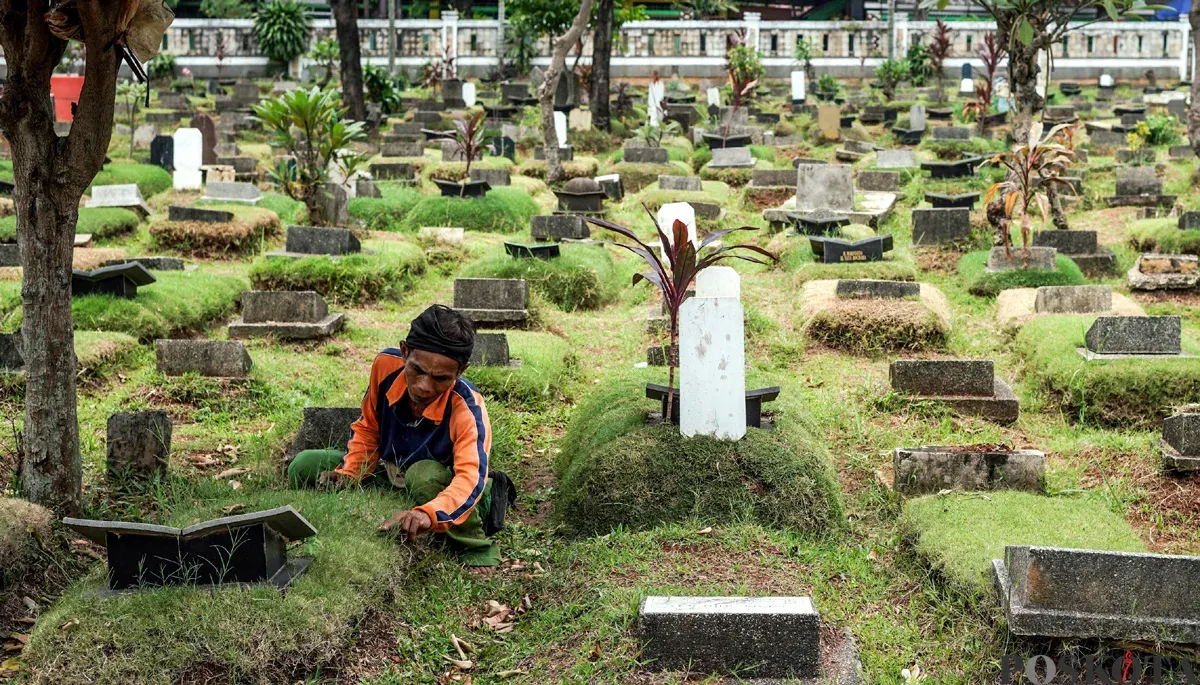 Petugas sedang membersihkan rumput di TPU Grogol Selatan, Kecamatan Kebayoran Lama, Jakarta Selatan. (Sumber: POSKOTA | Foto: Bilal Nugraha Ginanjar)