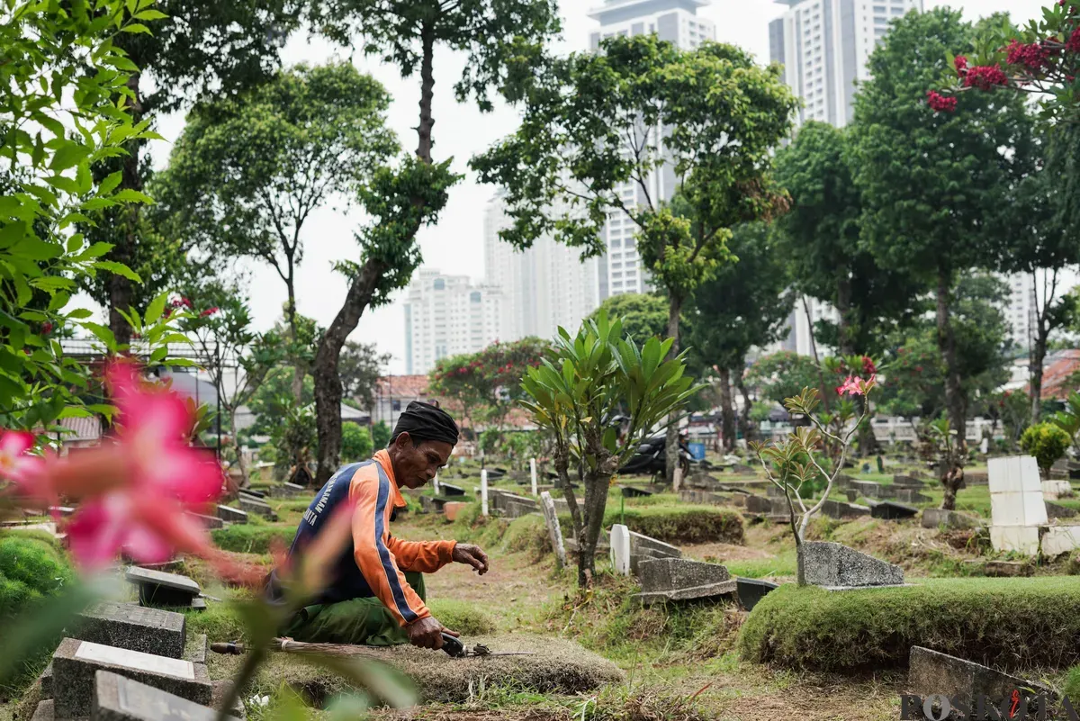 Petugas Suku Dinas Pertamanan dan Hutan Jakarta Selatan membersihkan salah satu makam di Tempat Pemakaman Umum (TPU) Grogol Selatan, Jakarta, Selasa, 21 Oktober 2025. (Sumber: Poskota/Bilal Nugraha Ginanjar)