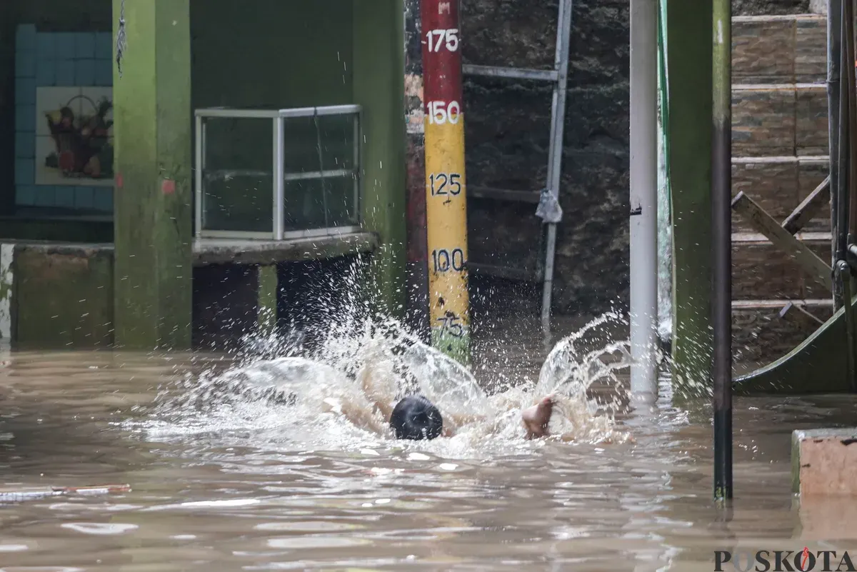 Warga berjalan melintasi banjir di Kebon Pala, Jatinegara, Jakarta Timur, Selasa, 28 Oktober 2025. (Sumber: Poskota/Bilal Nugraha Ginanjar)