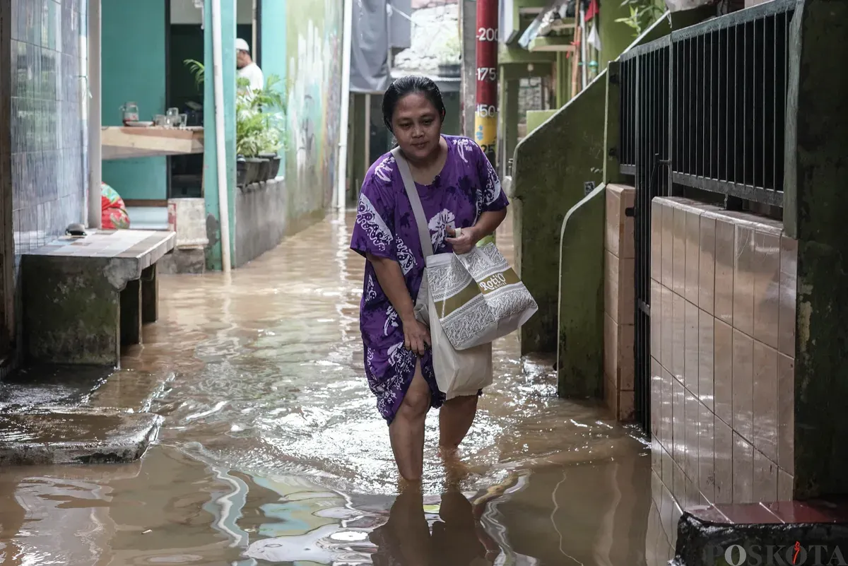 Warga berjalan melintasi banjir di Kebon Pala, Jatinegara, Jakarta Timur, Selasa, 28 Oktober 2025. (Sumber: Poskota/Bilal Nugraha Ginanjar)