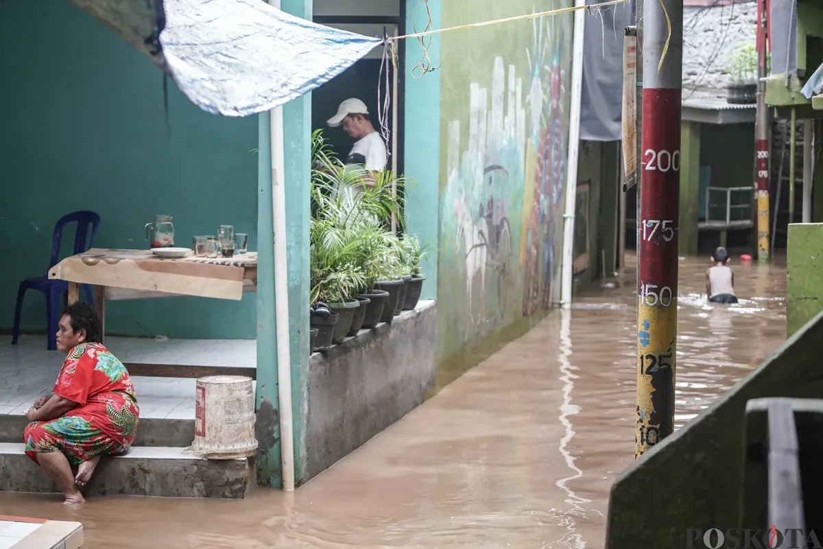 Warga berjalan melintasi banjir di Kebon Pala, Jatinegara, Jakarta Timur, Selasa, 28 Oktober 2025. (Sumber: Poskota/Bilal Nugraha Ginanjar)