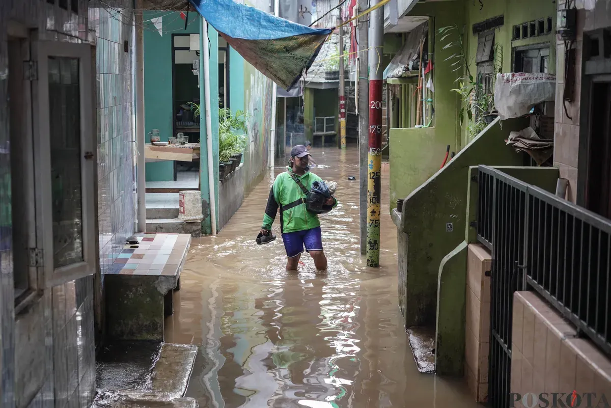 Warga berjalan melintasi banjir di Kebon Pala, Jatinegara, Jakarta Timur, Selasa, 28 Oktober 2025. (Sumber: Poskota/Bilal Nugraha Ginanjar)