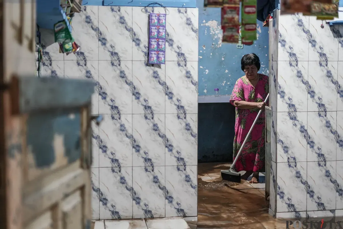 Warga berjalan melintasi banjir di Kebon Pala, Jatinegara, Jakarta Timur, Selasa, 28 Oktober 2025. (Sumber: Poskota/Bilal Nugraha Ginanjar)