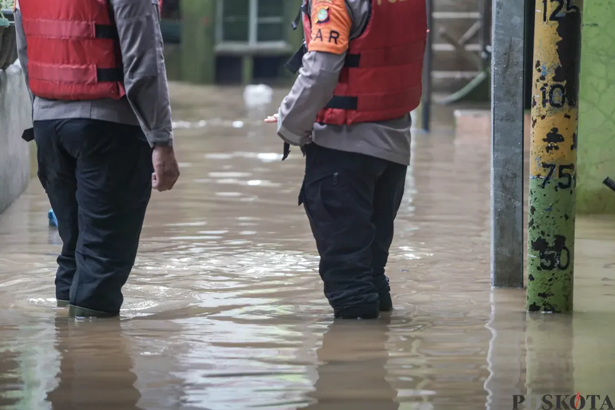 Warga berjalan melintasi banjir di Kebon Pala, Jatinegara, Jakarta Timur, Selasa, 28 Oktober 2025. (Sumber: Poskota/Bilal Nugraha Ginanjar)