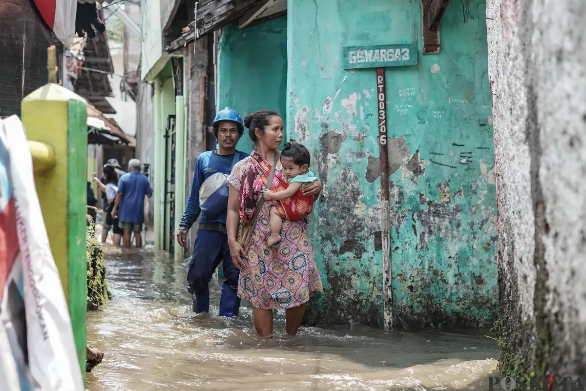 Warga berjalan menerobos banjir yang melanda kawasan RT 03, RW 06, Jati Padang, Pasar Minggu Jakarta Selatan, Jumat, 31 Oktober 2025. (Sumber: Poskota/Bilal Nugraha Ginanjar)