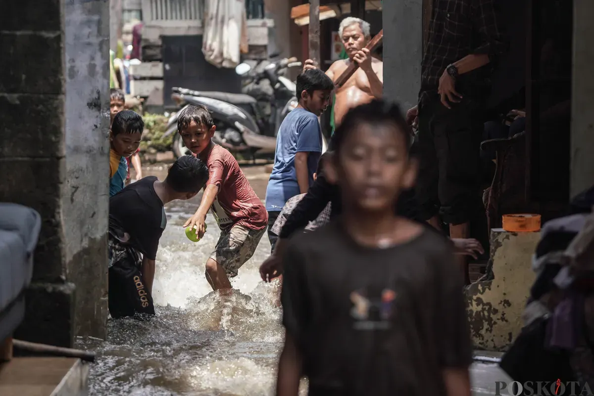 Anak-anak bermain air genangan banjir yang melanda kawasan RT 03, RW 06, Jati Padang, Pasar Minggu Jakarta Selatan, Jumat, 31 Oktober 2025. (Sumber: Poskota/Bilal Nugraha Ginanjar)