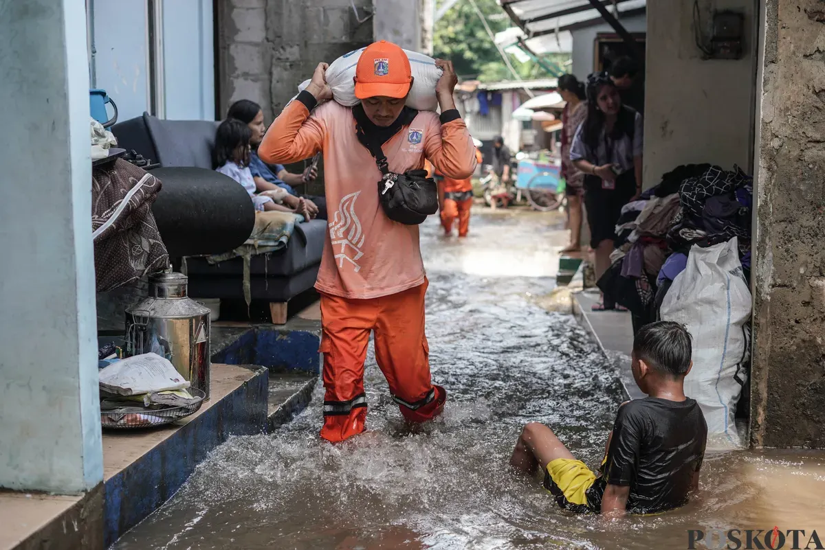 Petugas PPSU membawa karung berisi pasir untuk menghalangi air masuk di dekat tanggul yang jebol di kawasan RT 03, RW 06, Jati Padang, Pasar Minggu Jakarta Selatan, Jum'at, 31 Oktober 2025. (Sumber: Poskota/Bilal Nugraha Ginanjar)