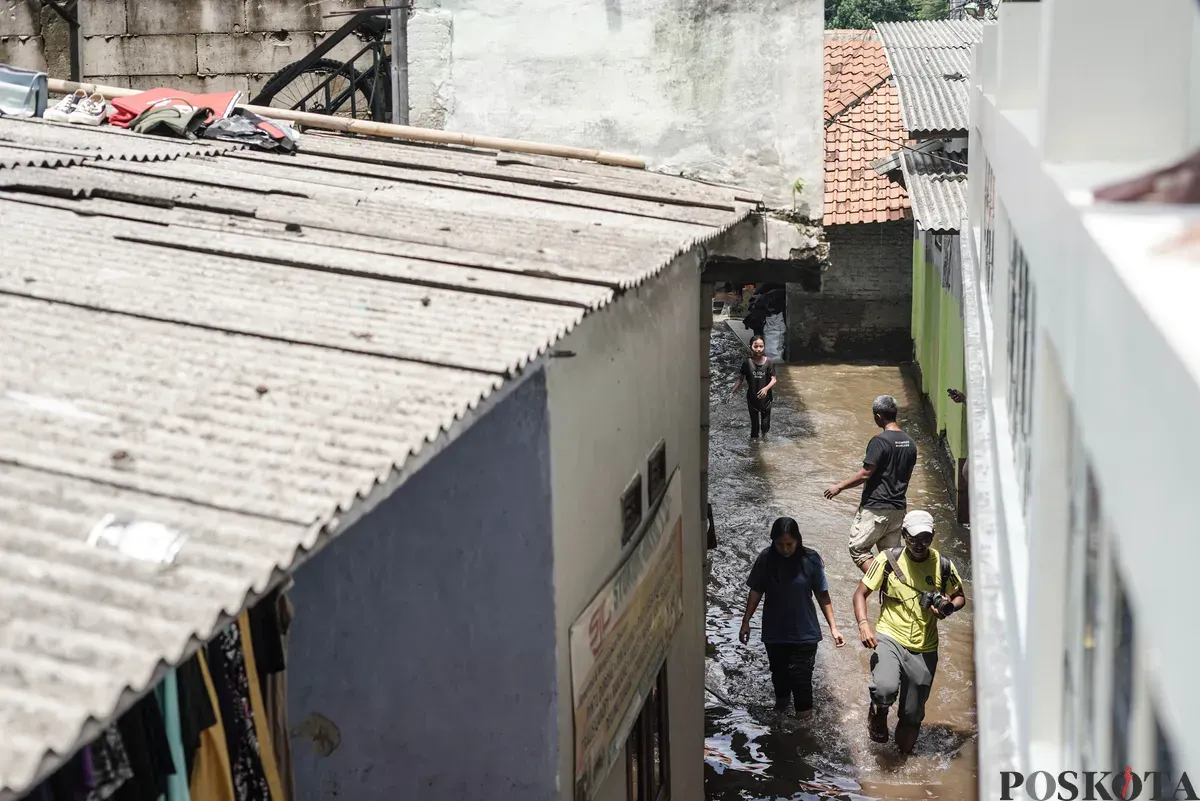 Warga berjalan menerobos banjir yang melanda kawasan RT 03, RW 06, Jati Padang, Pasar Minggu Jakarta Selatan, Jumat, 31 Oktober 2025. (Sumber: Poskota/Bilal Nugraha Ginanjar)