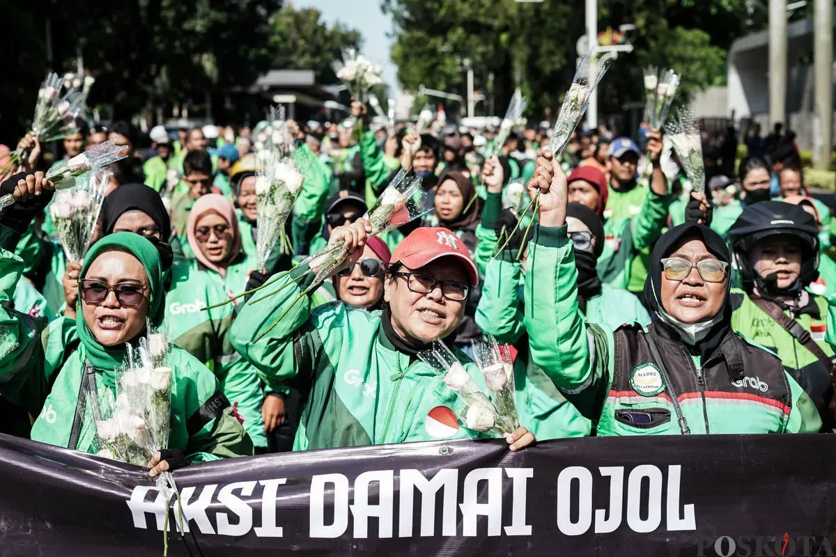 Sejumlah pengemudi ojek daring (ojol) membagikan bunga kepada petugas di kawasan Monumen Nasional, Jakarta, Selasa, 2 September 2025. (Sumber: Poskota/Bilal Nugraha Ginanjar)