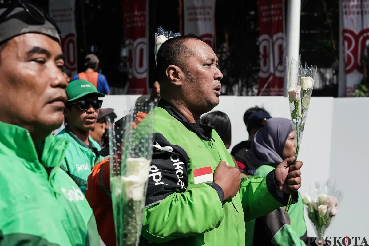 Sejumlah pengemudi ojek daring (ojol) membagikan bunga kepada petugas di kawasan Monumen Nasional, Jakarta, Selasa, 2 September 2025. (Sumber: Poskota/Bilal Nugraha Ginanjar)