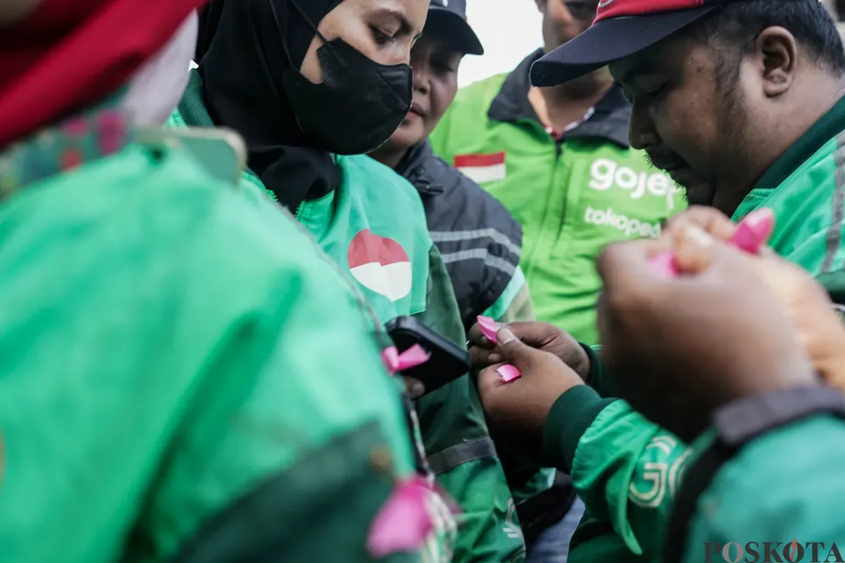 Sejumlah pengemudi ojek daring (ojol) membagikan bunga kepada petugas di kawasan Monumen Nasional, Jakarta, Selasa, 2 September 2025. (Sumber: Poskota/Bilal Nugraha Ginanjar)