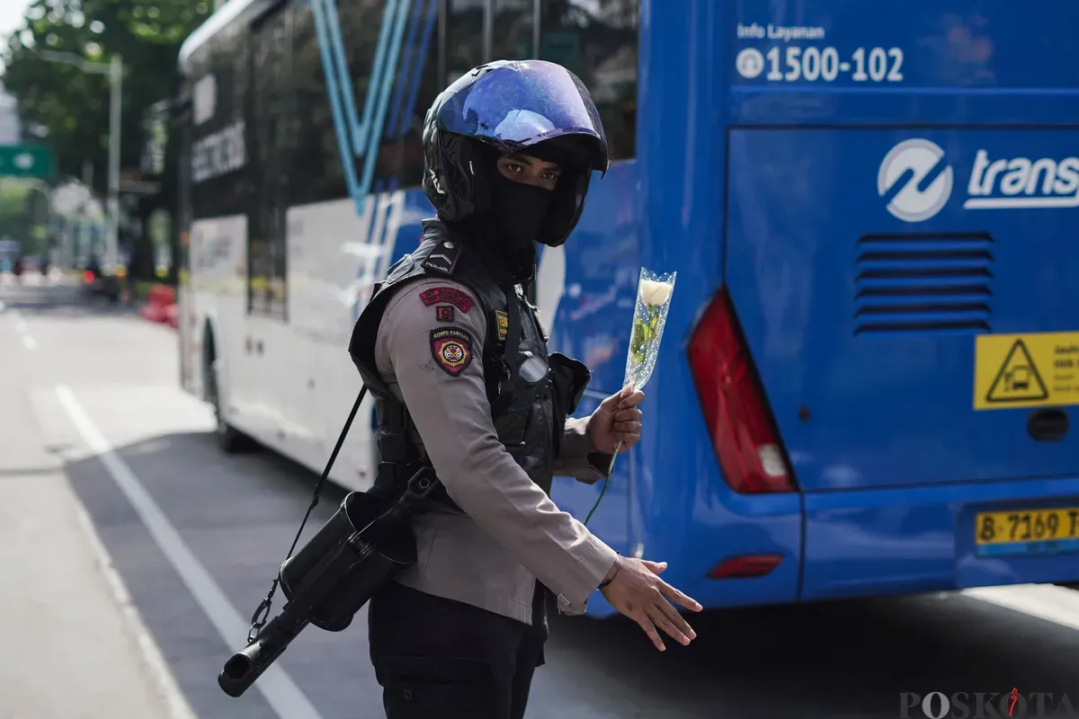 Sejumlah pengemudi ojek daring (ojol) membagikan bunga kepada petugas di kawasan Monumen Nasional, Jakarta, Selasa, 2 September 2025. (Sumber: Poskota/Bilal Nugraha Ginanjar)