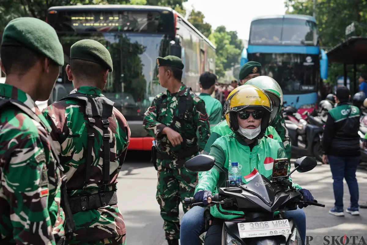 Sejumlah pengemudi ojek daring (ojol) membagikan bunga kepada petugas di kawasan Monumen Nasional, Jakarta, Selasa, 2 September 2025. (Sumber: Poskota/Bilal Nugraha Ginanjar)