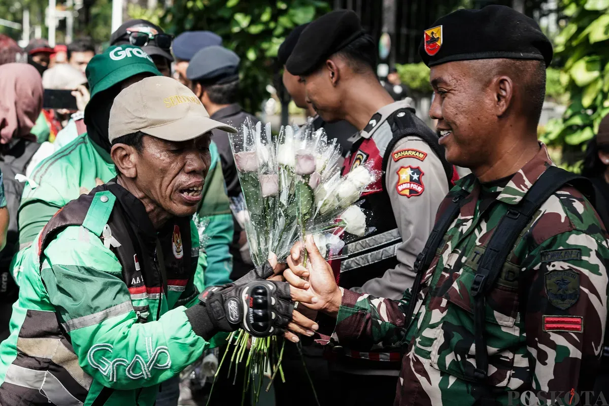 Sejumlah pengemudi ojek daring (ojol) membagikan bunga kepada petugas di kawasan Monumen Nasional, Jakarta, Selasa, 2 September 2025. (Sumber: Poskota/Bilal Nugraha Ginanjar)