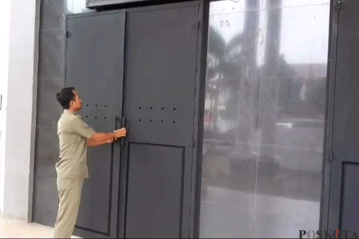 Salah seorang petugas Satpol PP saat memperlihatkan pintu baja di depan Kantor Bupati Pandeglang. (Sumber: Poskota/Samsul Fatoni)
