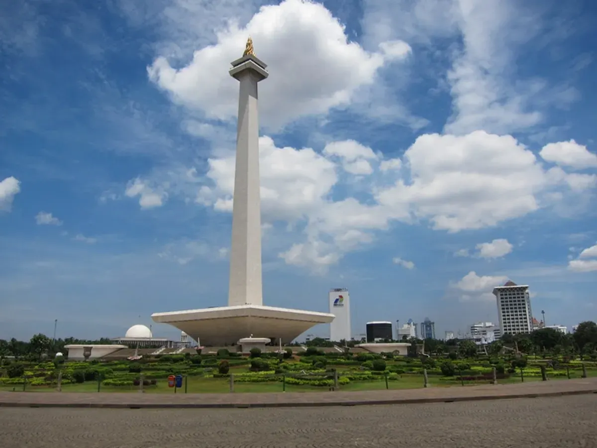 Monumen Nasional (Monas) menjulang megah sebagai ikon Jakarta, dikelilingi taman hijau yang ramai pengunjung. (Sumber: Pinterest)