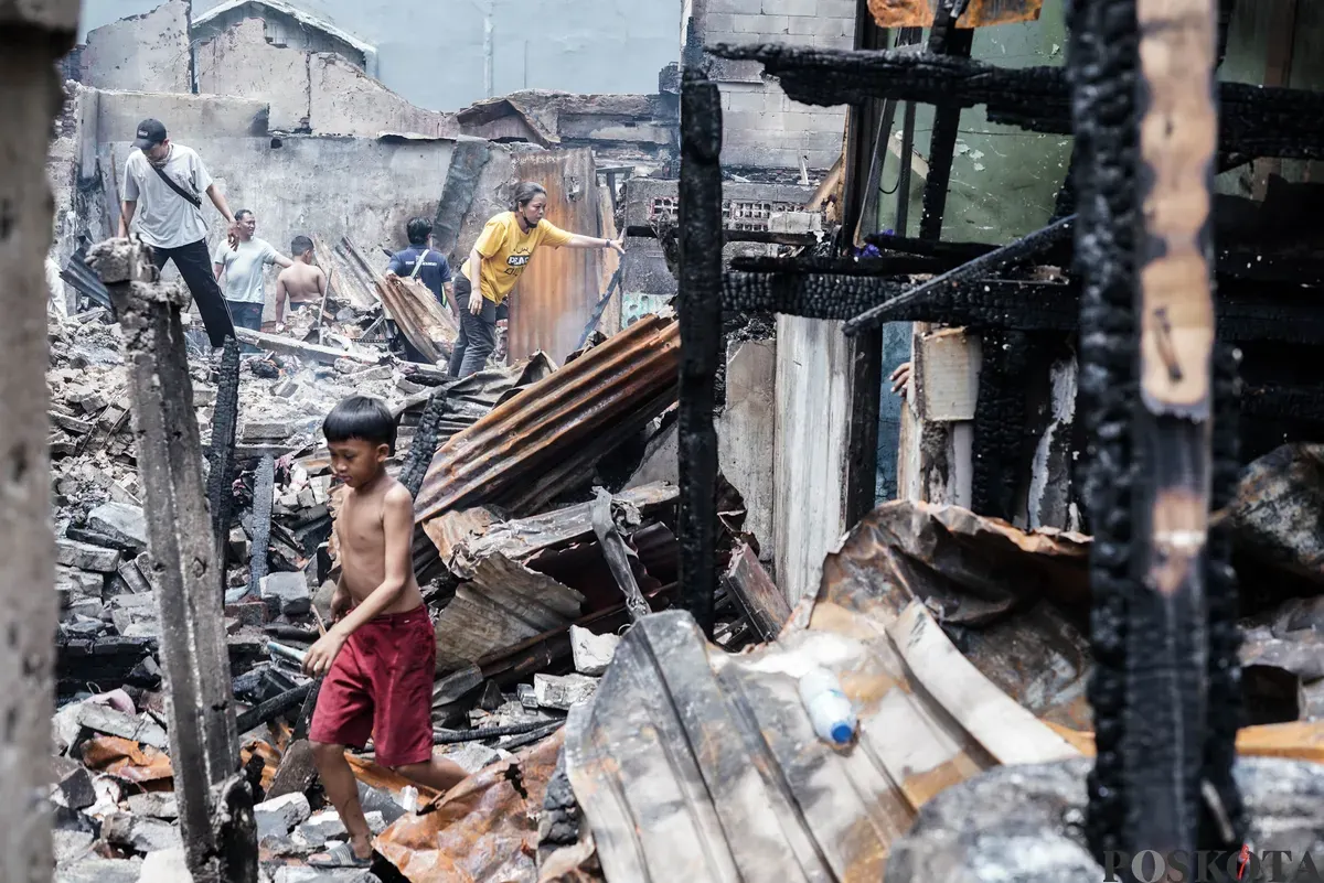 Warga membawa barang-barang yang masih bisa diselamatkan dari kebakaran di Senen, Jakarta Pusat, Senin, 15 September 2025. (Sumber: Poskota/Bilal Nugraha Ginanjar)