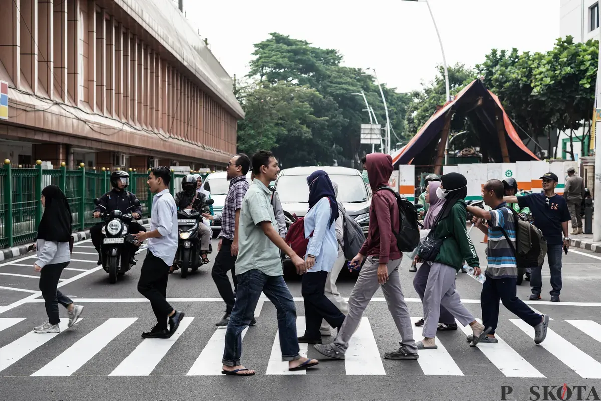 Warga menyeberang jalan menggunakan pelican crossing di sisi timur Stasiun Cikini, Jakarta, Senin, 15 September 2025. (Sumber: Poskota/Bilal Nugraha Ginanjar)