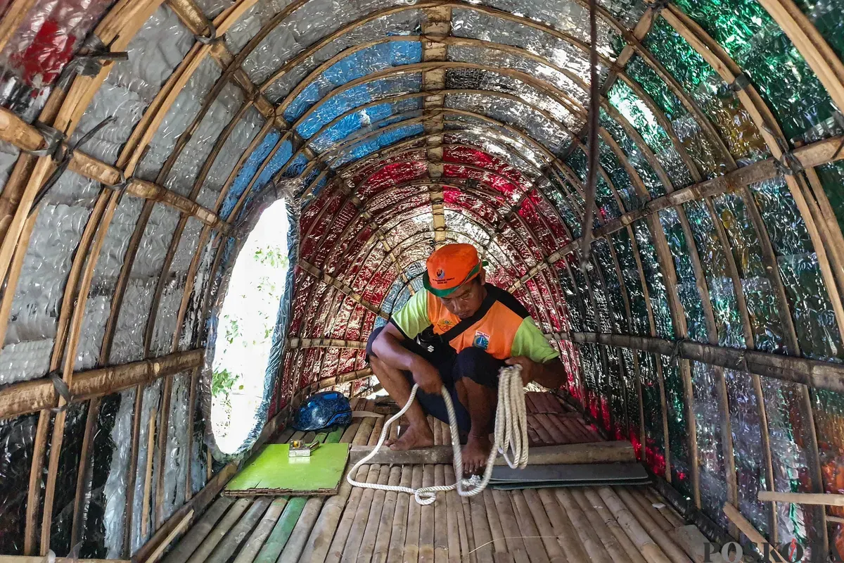 Petugas Unit Pengananan Sampah (UPS) Badan Air Kecamatan Johar Baru sibuk menyelesaikan perahu berbentuk ikan hiu di Johar Baru, Jakarta Pusat, Minggu, 21 September 2025. (Sumber: Poskota/Bilal Nugraha Ginanjar)
