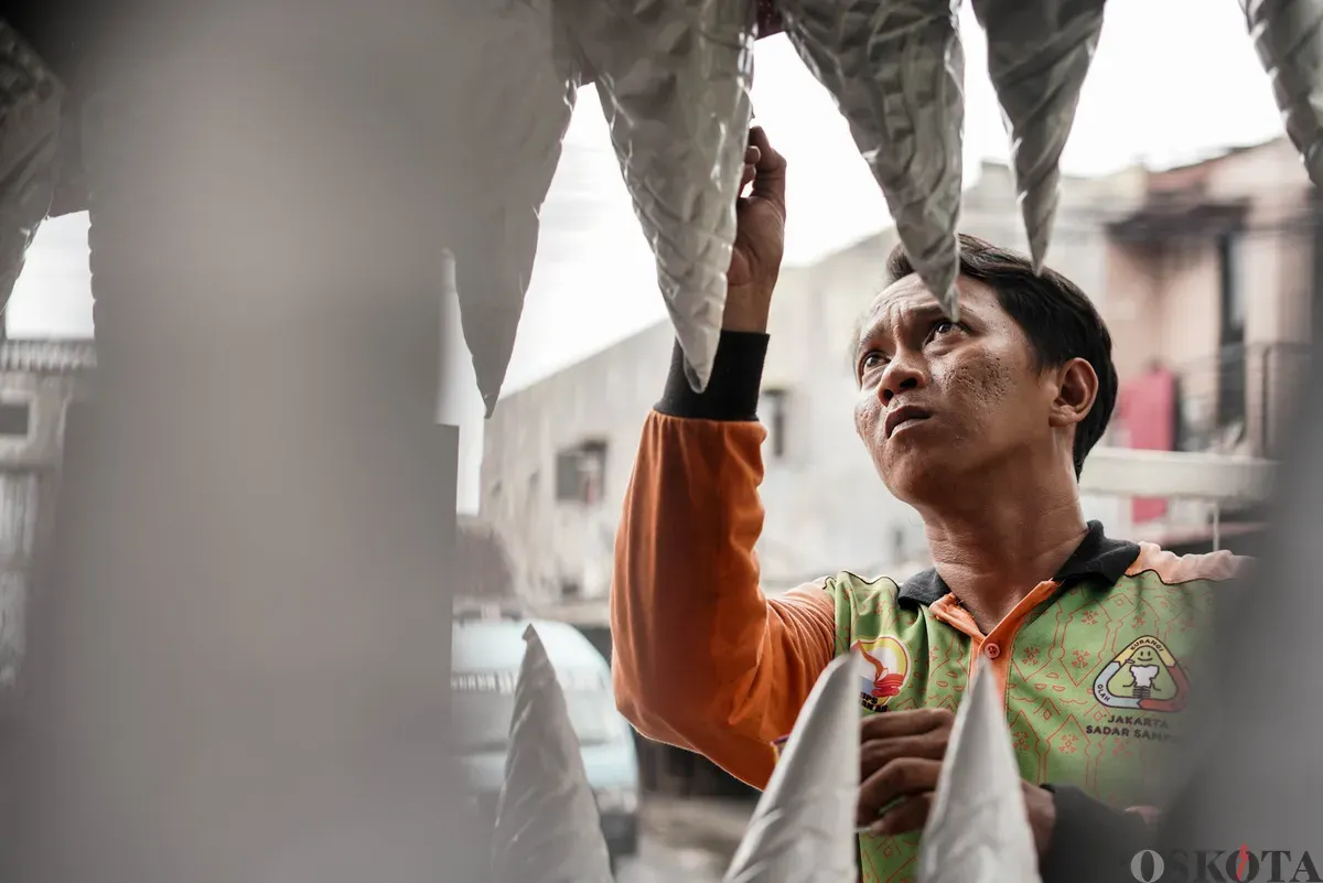Petugas Unit Pengananan Sampah (UPS) Badan Air Kecamatan Johar Baru sibuk menyelesaikan perahu berbentuk ikan hiu di Johar Baru, Jakarta Pusat, Minggu, 21 September 2025. (Sumber: Poskota/Bilal Nugraha Ginanjar)