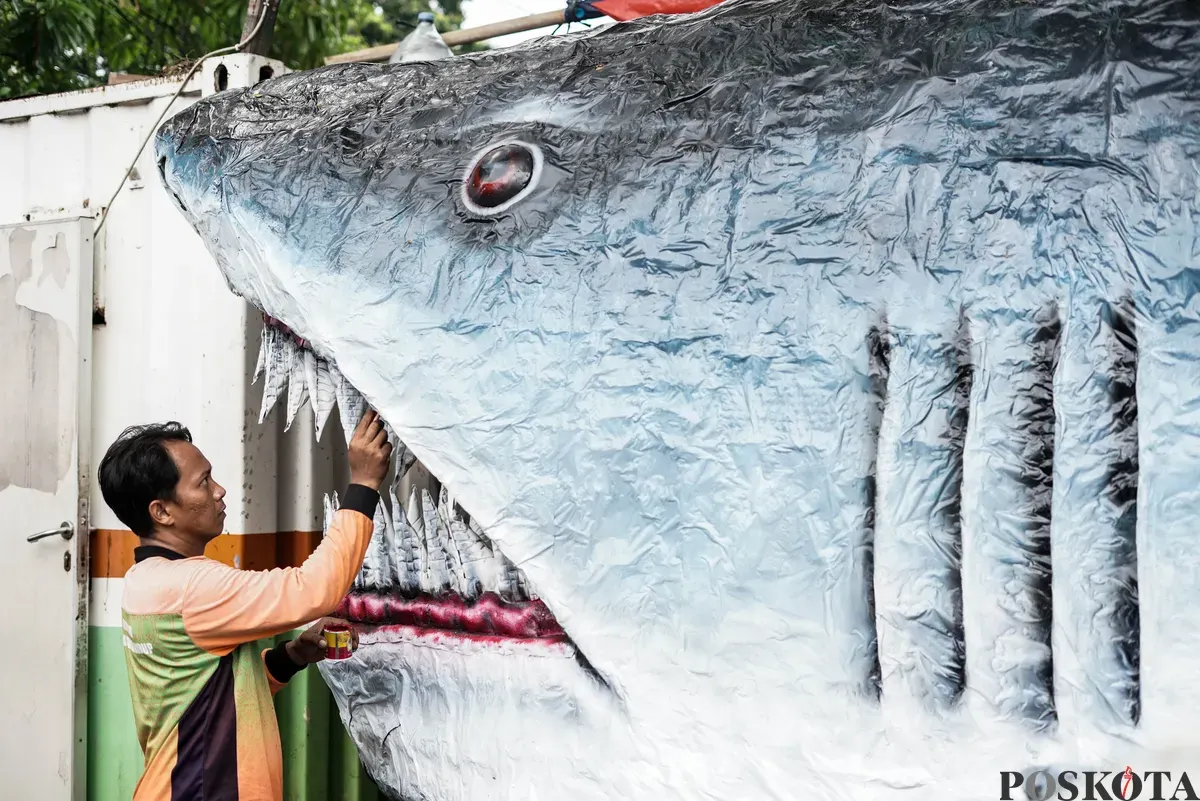 Petugas Unit Pengananan Sampah (UPS) Badan Air Kecamatan Johar Baru sibuk menyelesaikan perahu berbentuk ikan hiu di Johar Baru, Jakarta Pusat, Minggu, 21 September 2025. (Sumber: Poskota/Bilal Nugraha Ginanjar)