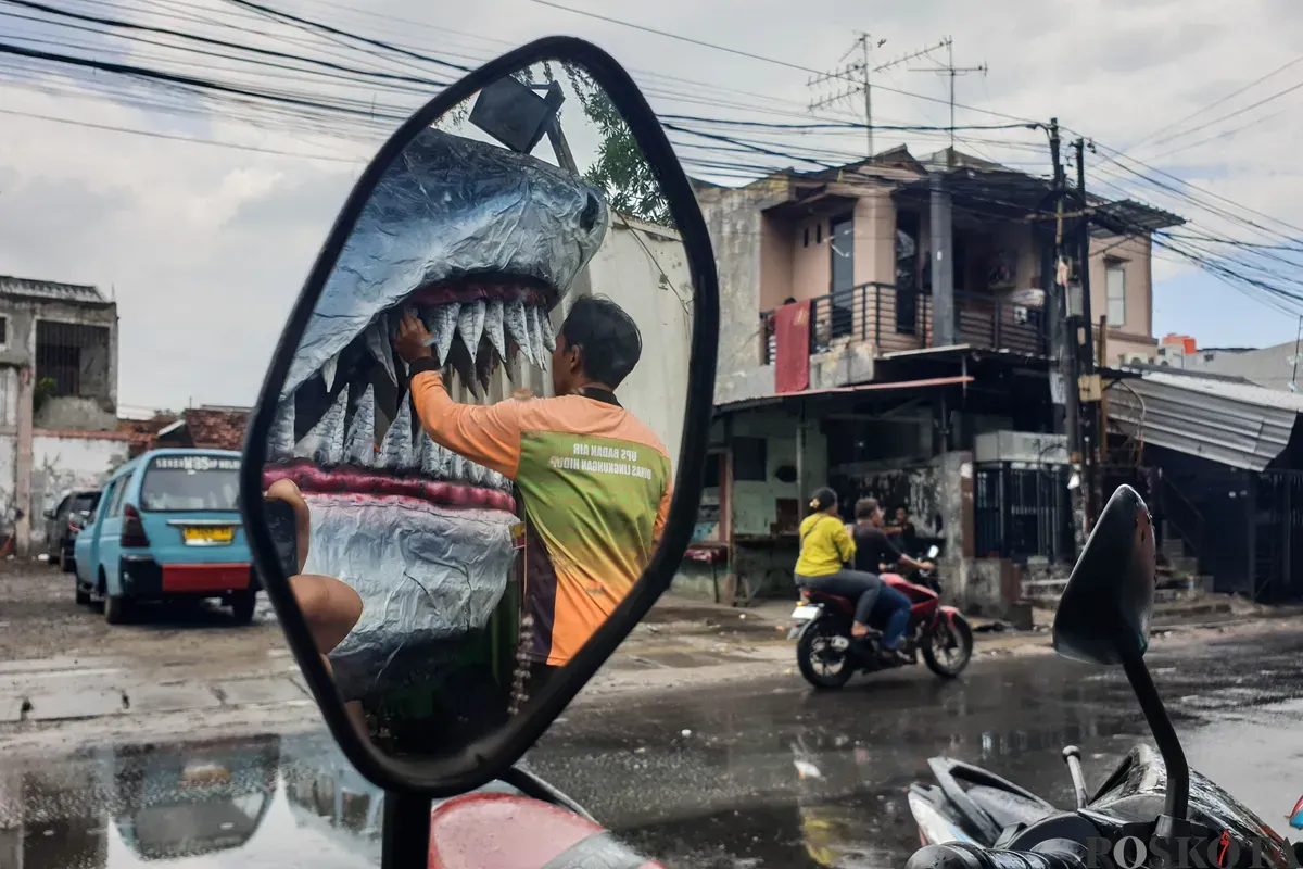 Petugas Unit Pengananan Sampah (UPS) Badan Air Kecamatan Johar Baru sibuk menyelesaikan perahu berbentuk ikan hiu di Johar Baru, Jakarta Pusat, Minggu, 21 September 2025. (Sumber: Poskota/Bilal Nugraha Ginanjar)