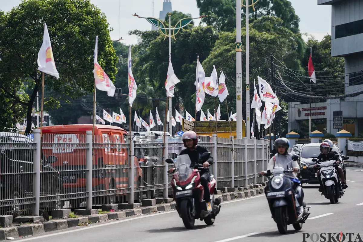 Pengendara sepeda motor melintas di dekat bendera partai politik yang terpasang di Jalan Layang Kemanggisan dan Jalan Pejompongan, Jakarta, Jumat, 6 Februari 2026. (Sumber: Poskota/Bilal Nugraha Ginanjar)