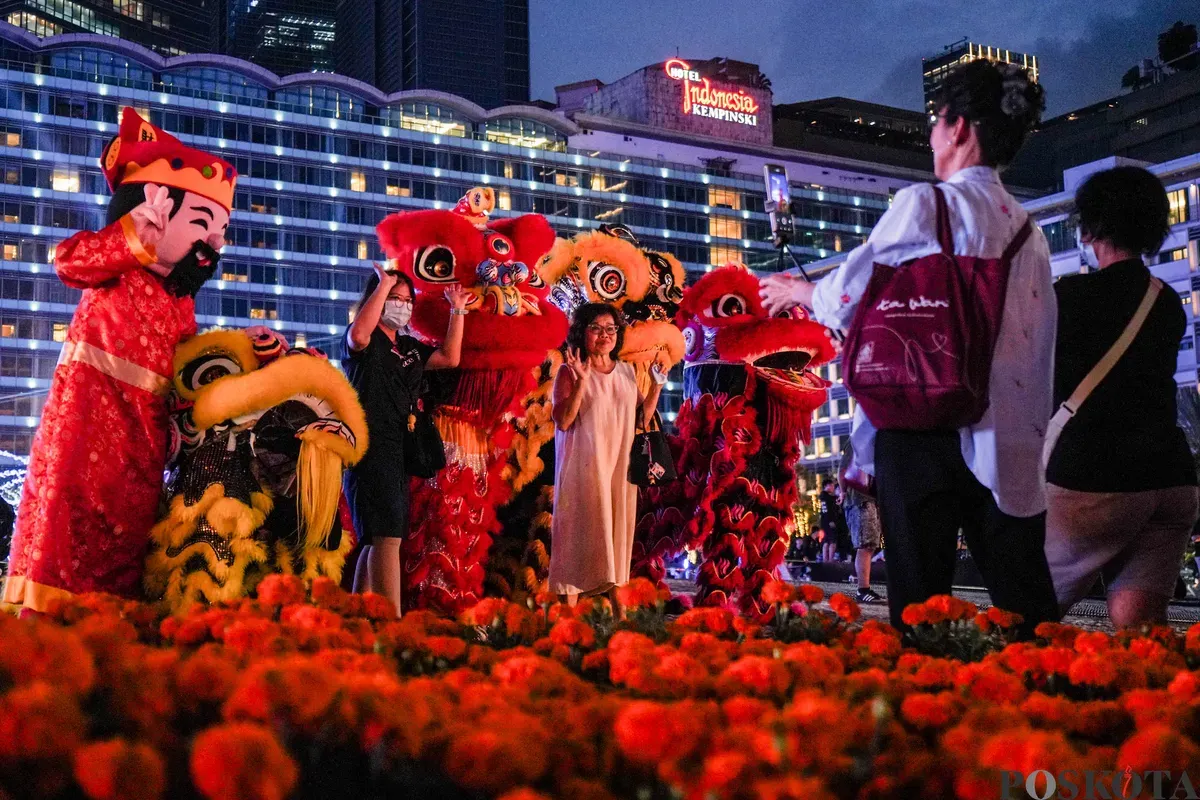 Warga berfoto dengan penari barongsai pada Festival Imlek Jakarta di kawasan Bundaran HI, Jakarta, Jumat, 13 Februari 2026. (Sumber: Poskota/Bilal Nugraha Ginanjar)