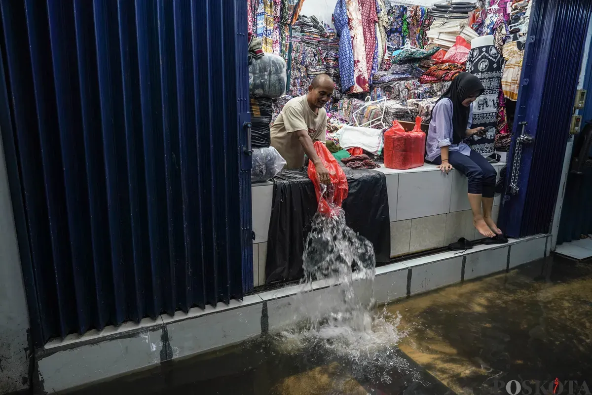 Pedagang mengeluarkan air banjir dari dalam kiosnya di Pasar Cipulir, Jakarta Selatan, Jumat, 20 Februari 2026. (Sumber: Poskota/Bilal Nugraha Ginanjar)