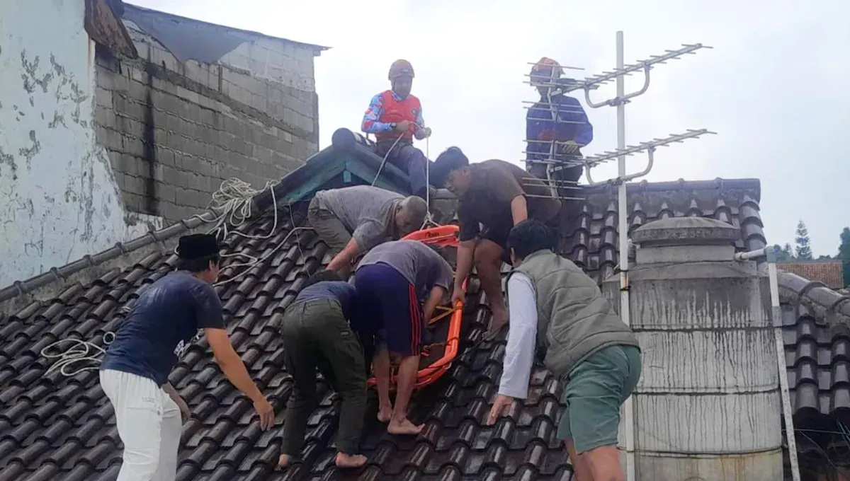 Petugas Damkar dibantu warga mengevakuasi korban yang meninggal saat membetulkan genteng rumah di Bogor. (Sumber: Damkar Bogor)