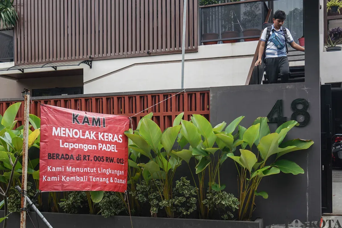 Warga berjalan melewati spanduk penolakan lapangan padel di Jalan Pulomas Barat II, Kayu Putih, Jakarta Timur, Minggu, 22 Februari 2026. (Sumber: Poskota/Bilal Nugraha Ginanjar)